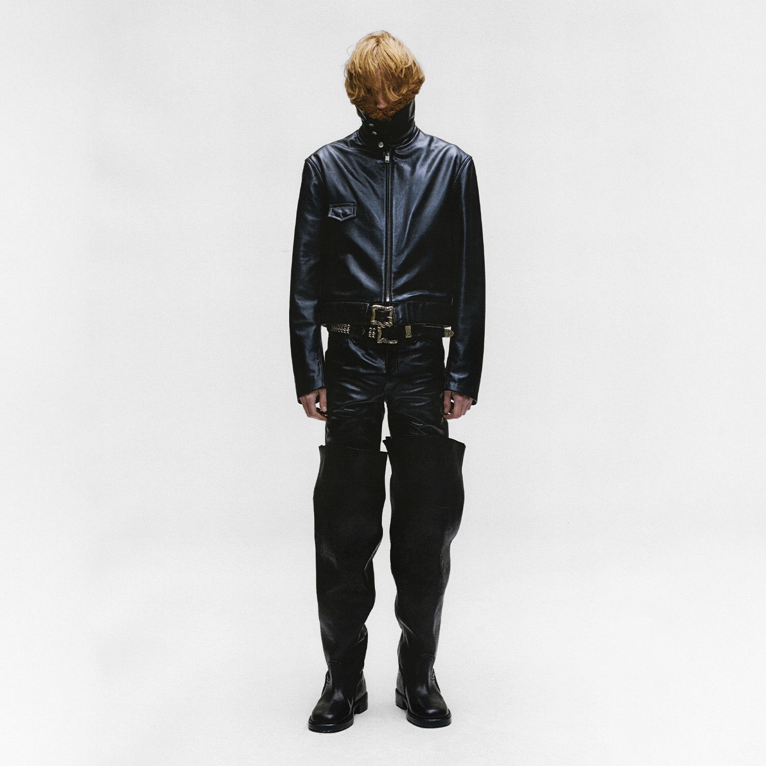 Male with red hair wearing a black enfants riches deprimes leather outfit on a white background