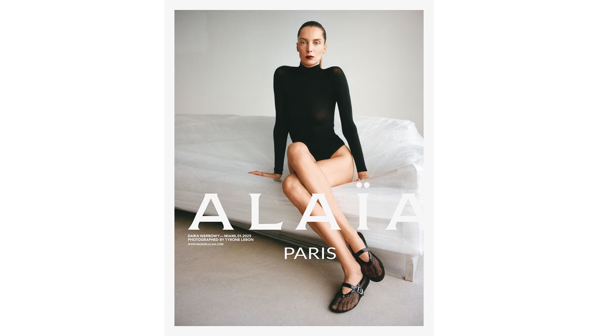 Alaia Model wearing a black outfit on a white couch.