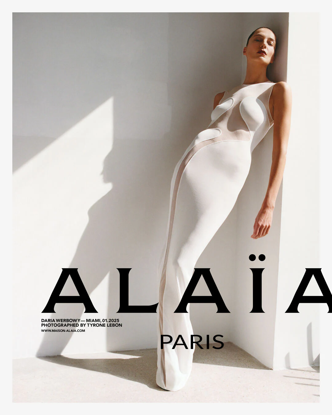 Model wearing a white Alaia dress with a minimalist background.