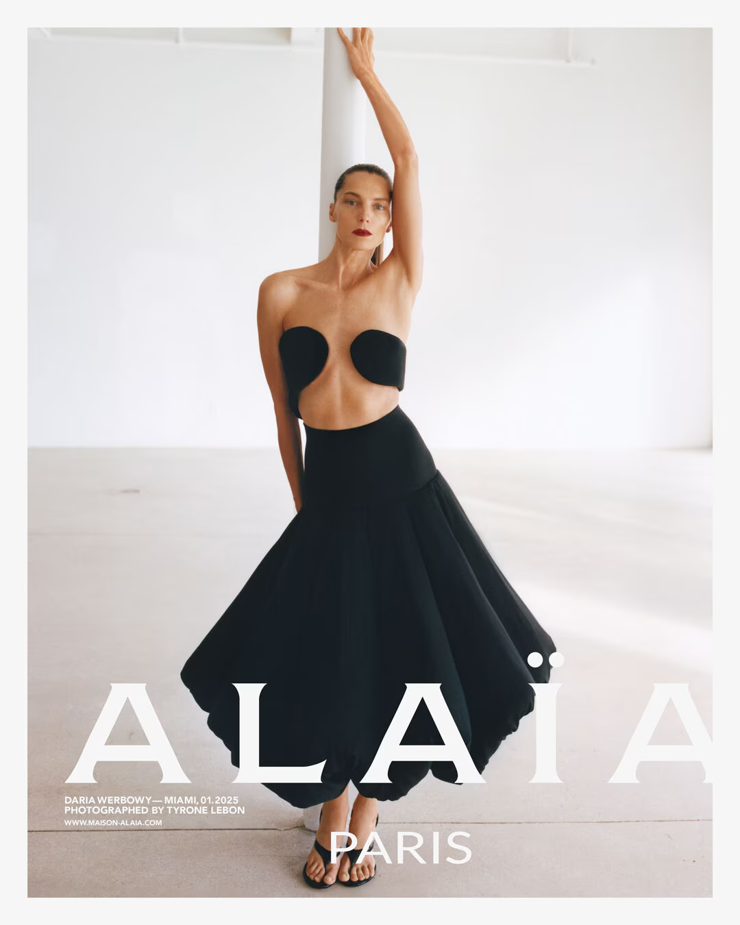 Model wearing a black Alaïa dress against a white background.