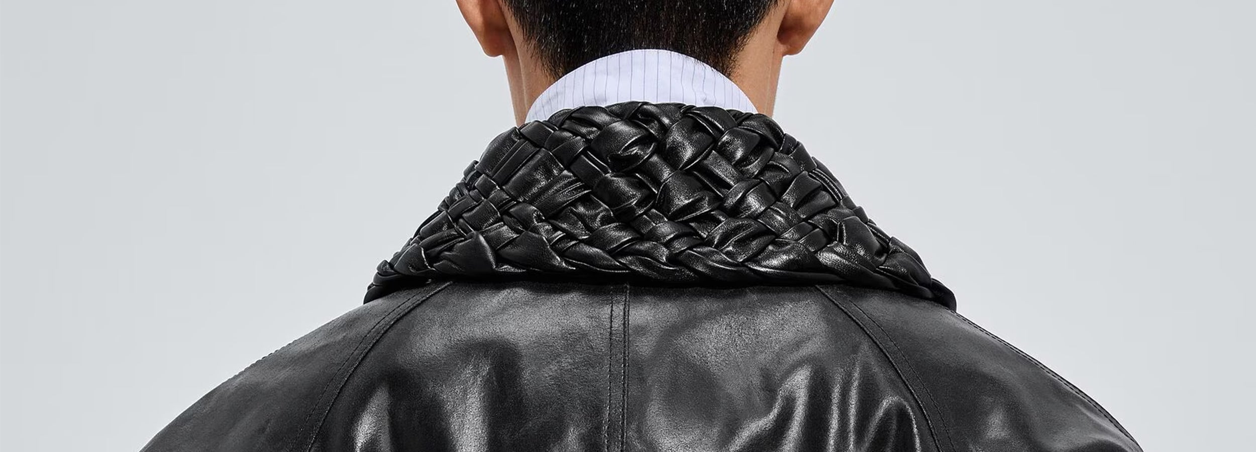 Person wearing a bottega veneta black leather jacket with woven detail