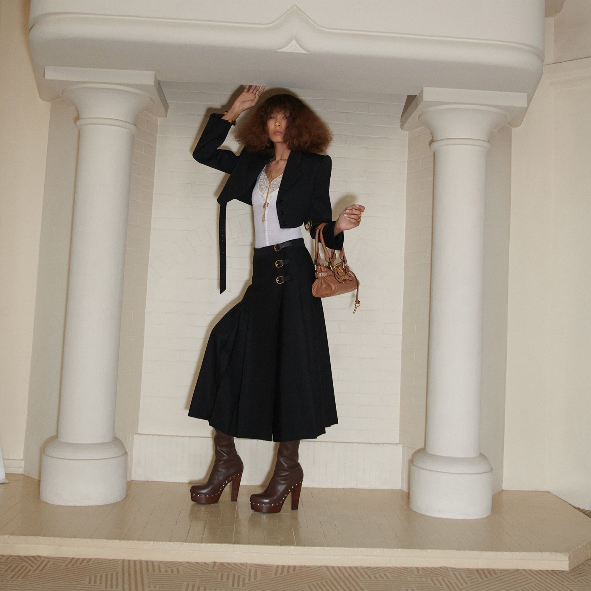 Woman with sculptural hair cut wearing a black chloe jacket and carrying a paddington bag