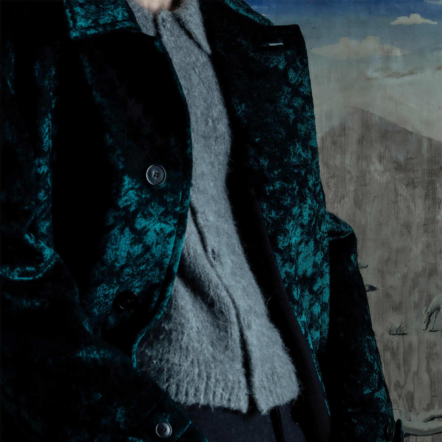 Close-up of a person wearing a Dries Van Voten coat with a mountainous landscape in the background