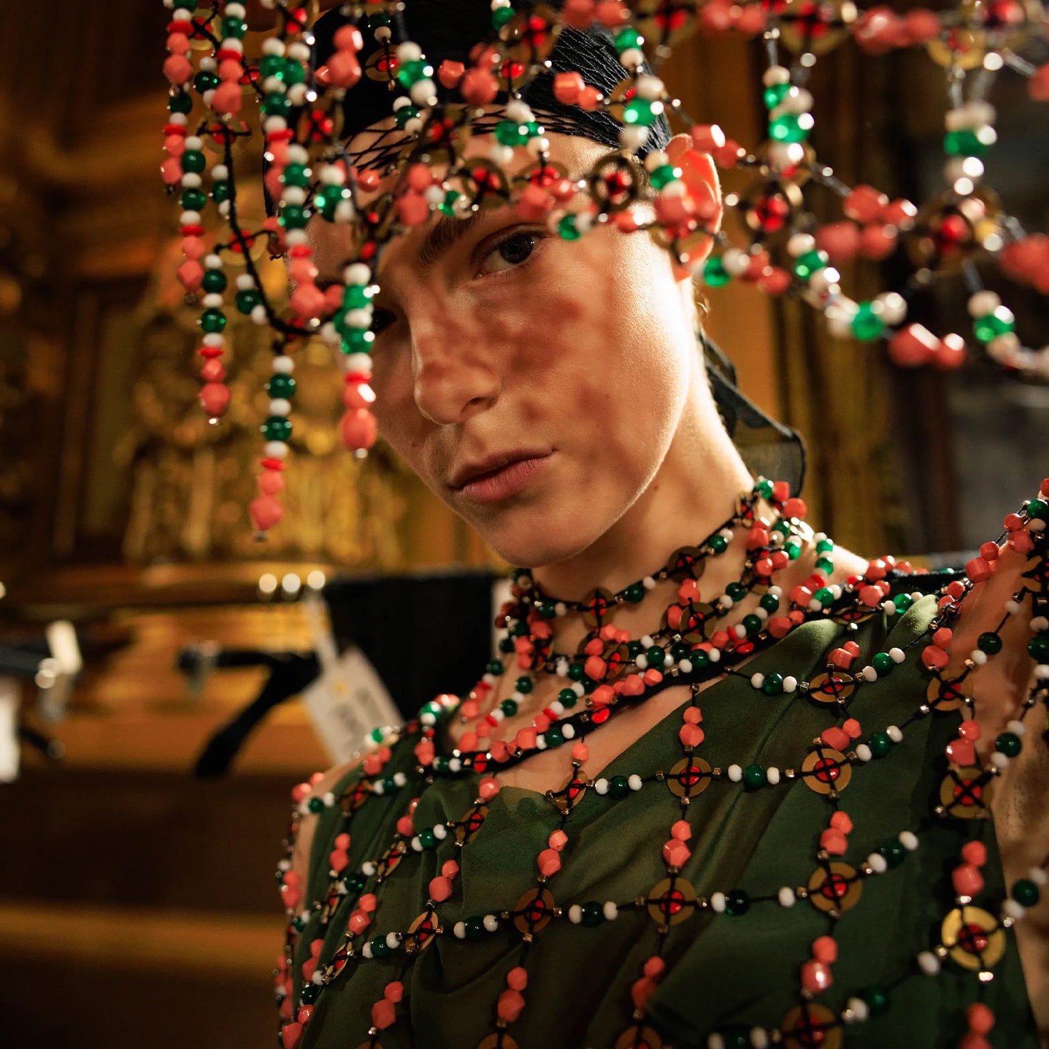 Person wearing a Dries Van Noten colorful beaded headpiece and necklace in a warm-toned setting for the Dries Van Noten FW25 Fashion show