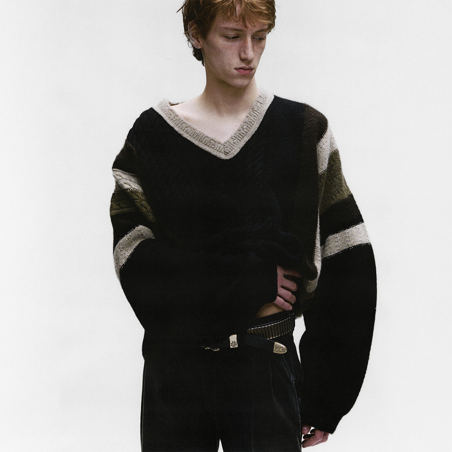 Male enfants riches deprimes wearing a black sweater with white and gray stripes on a white background