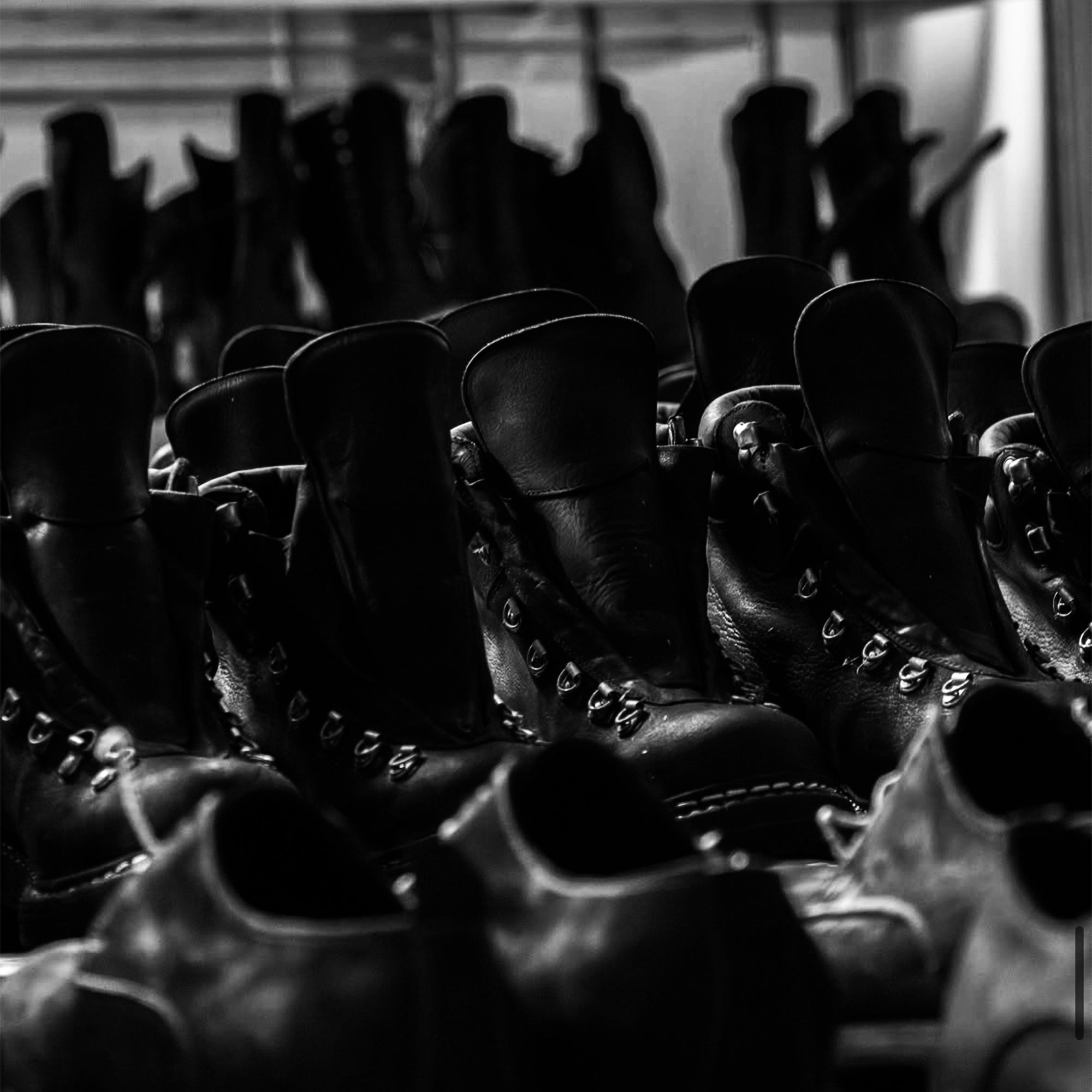 Stack of black leather guidi boots in a warehouse setting