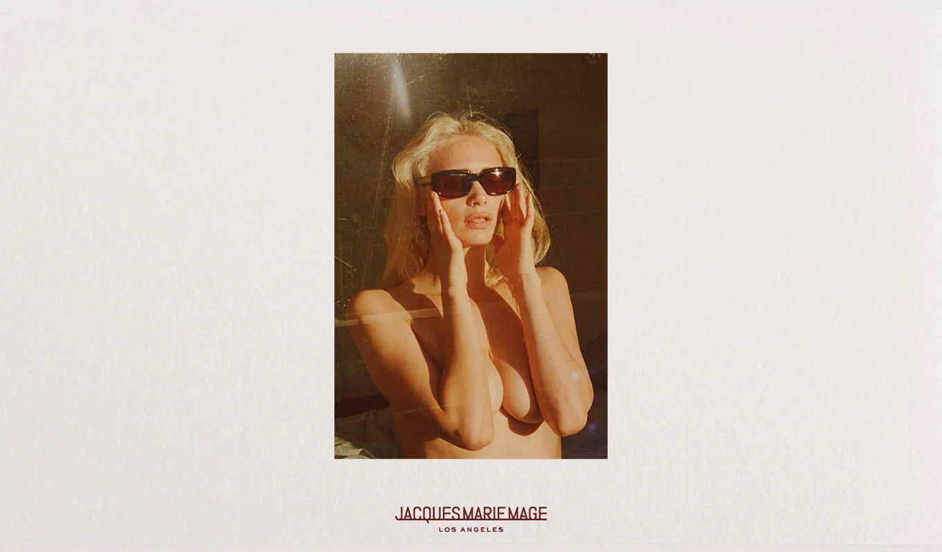 Nude woman wearing sunglasses with 'Jacques Marie Mage' branding on a white background