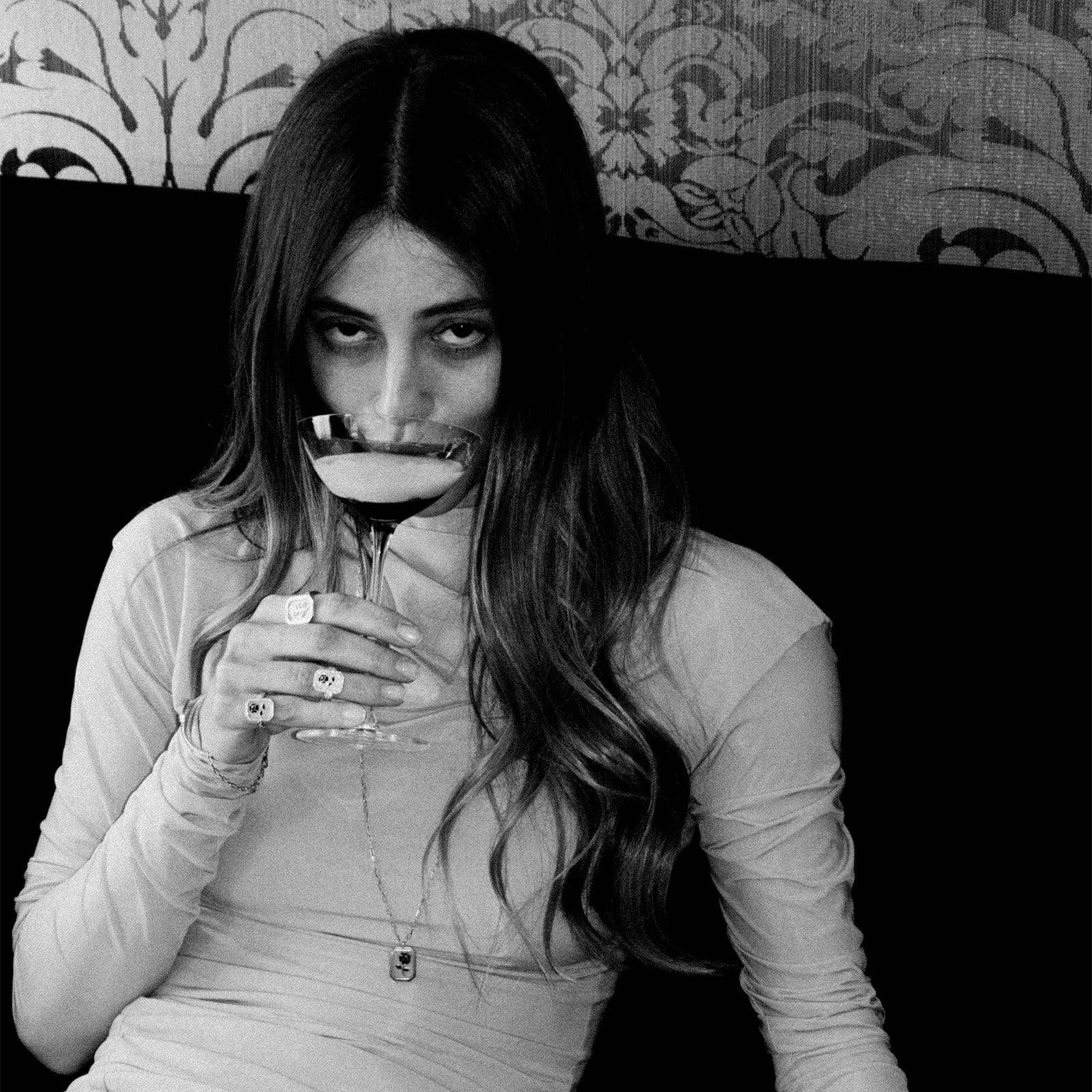 Black and white photo of a woman holding a glass to her lips.