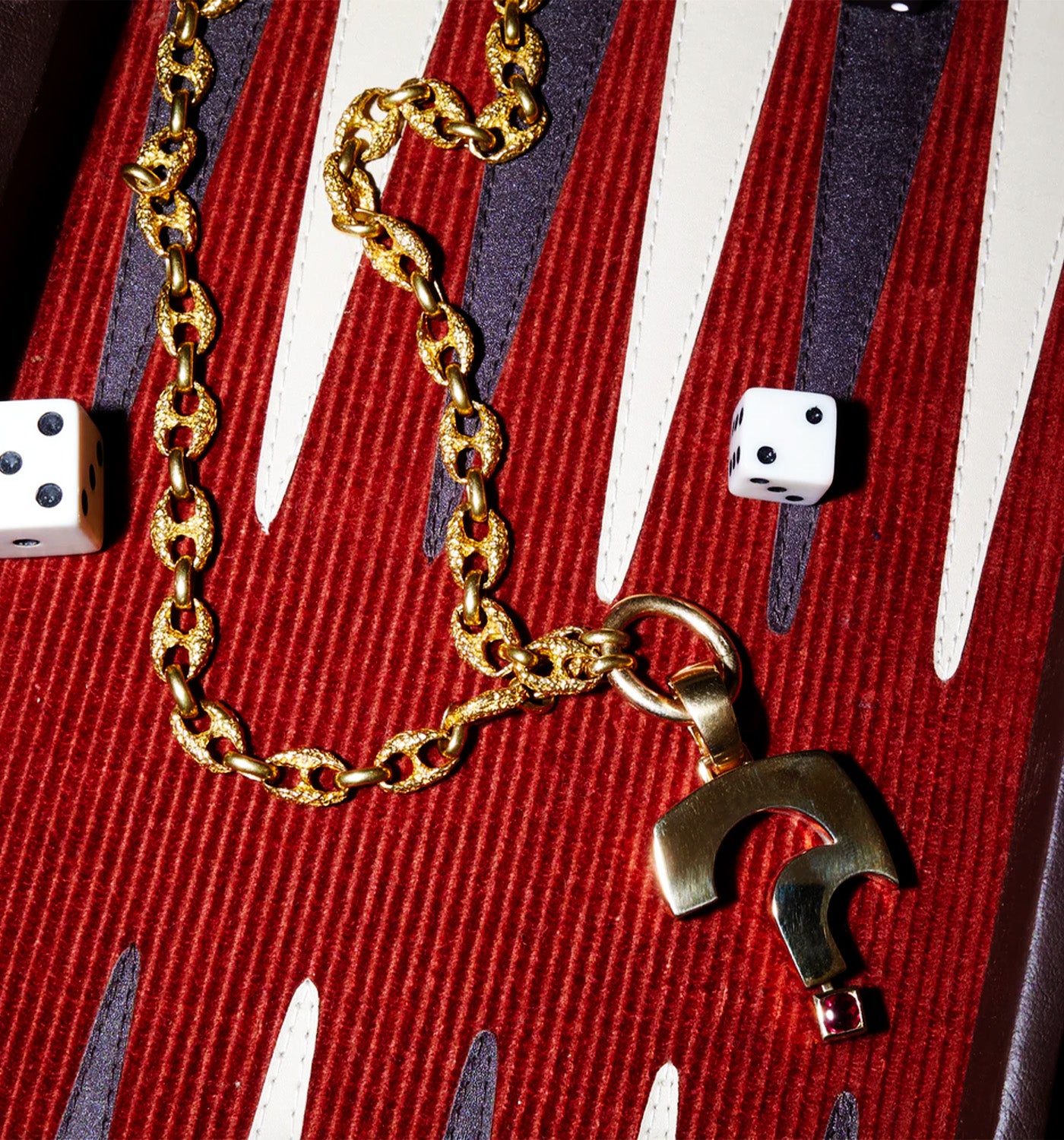 Renato Cipullo Gold chain necklace with a pendant on a backgammon board with dice.