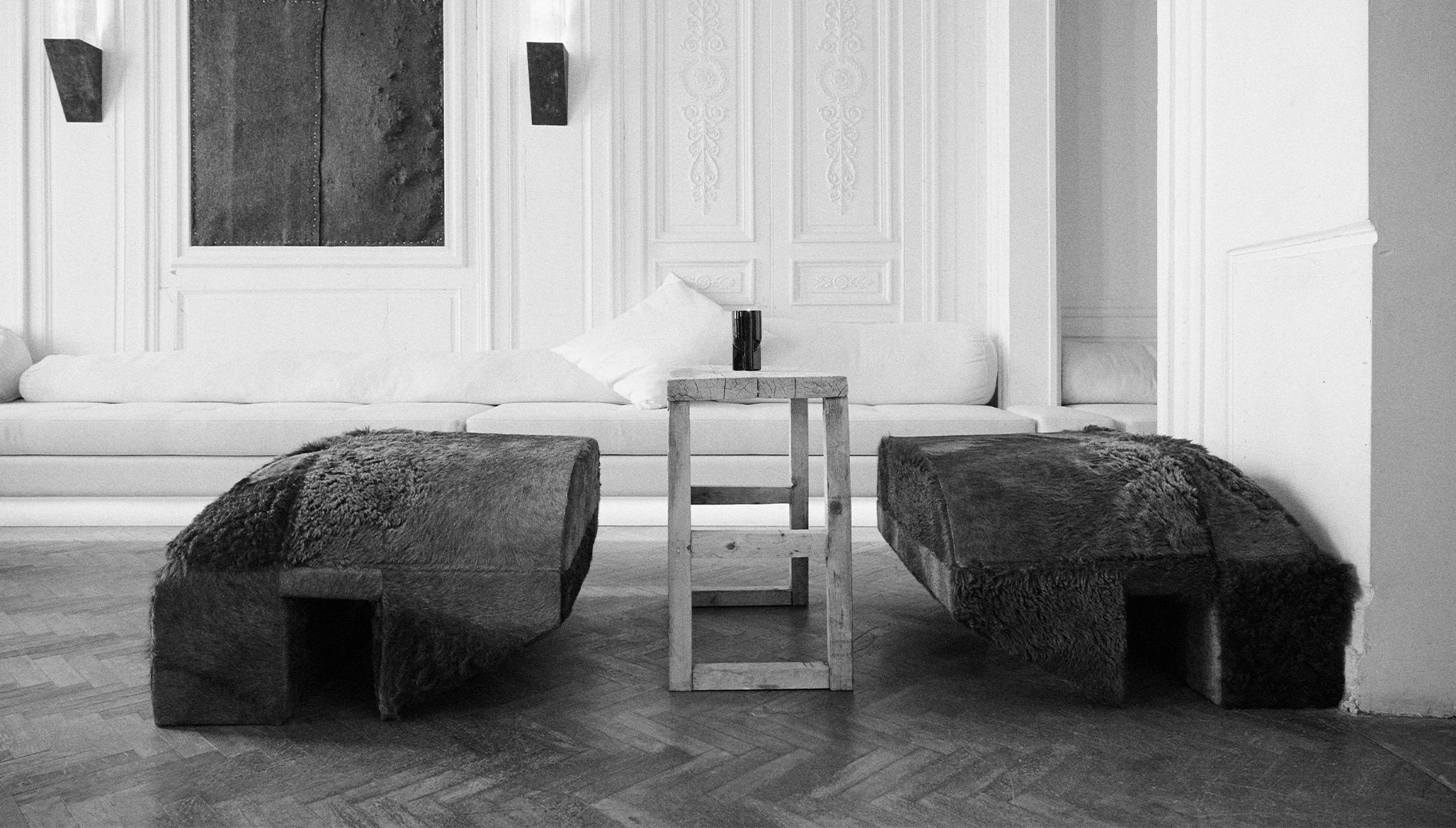 Modern Rick Owens interior with textured stone benches and a small table.