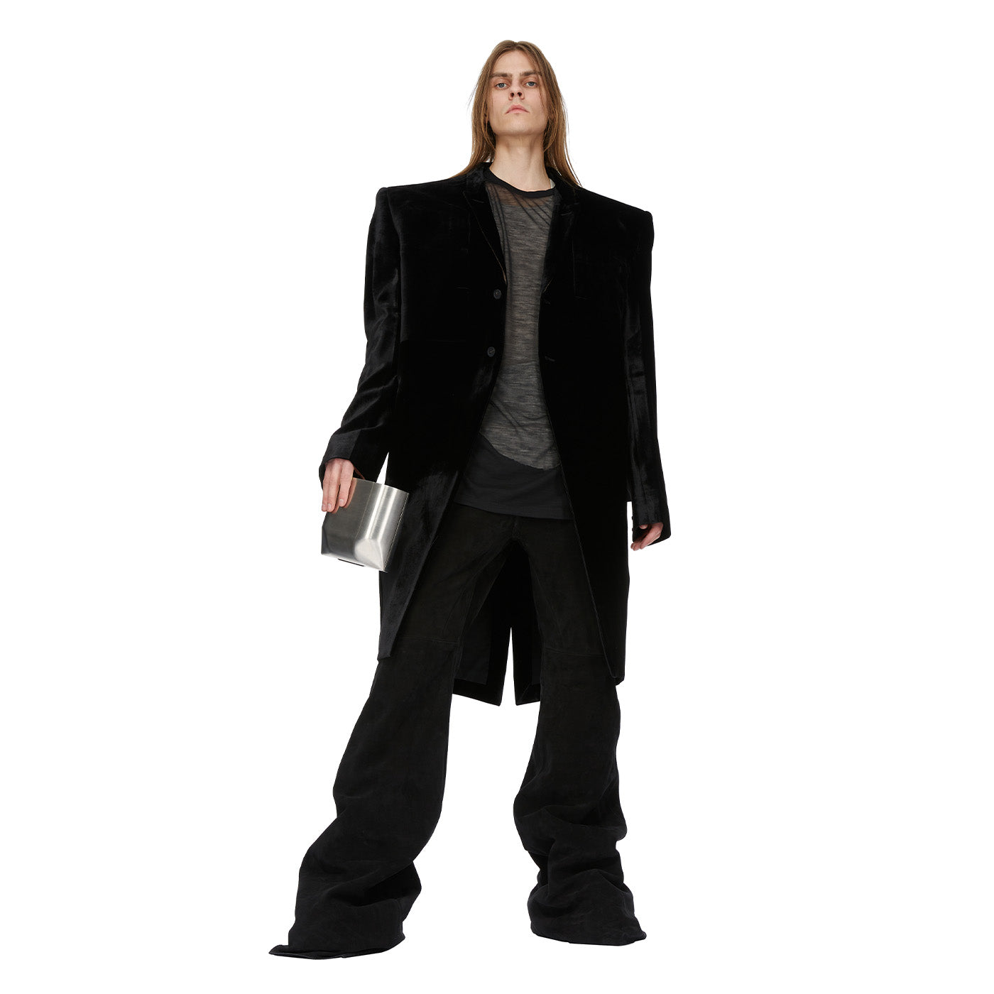 Person wearing a Rick Owens black coat and pants holding a silver clutch on a white background