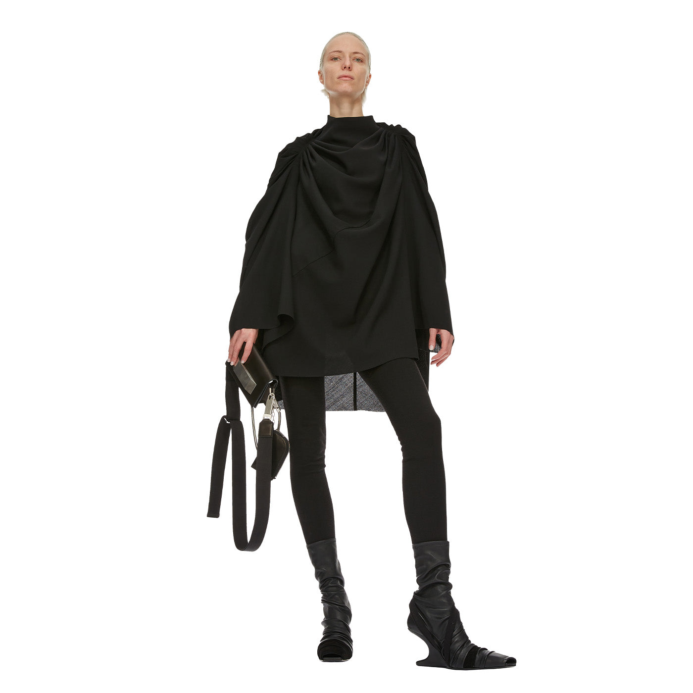 Person wearing a black Rick Owens outfit with a draped top and black shoes on a white background